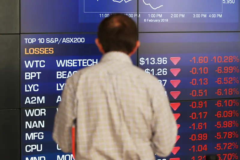 Mann foran skjerm som viser aksjekurser