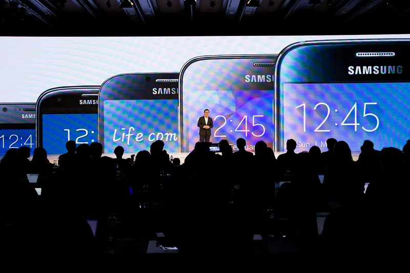 Mann på scenen med store mobiltelefoner på skjerm bak.